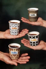 Four branded cups balanced on outstretched hands against a dark green ground