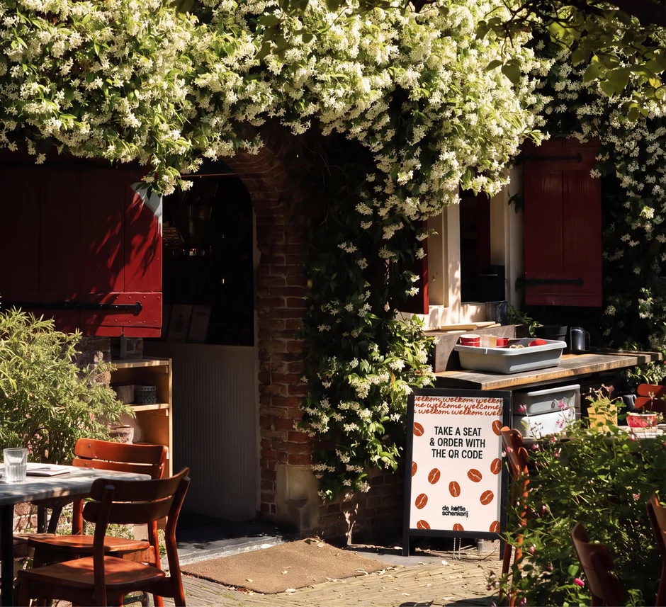 The terrace under flowering jasmine, with a QR ordering sign by the door