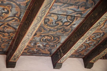 Painted beams and panels meeting the plastered sacristy wall