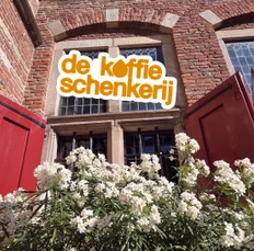 The signboard above the door, framed by flowering jasmine