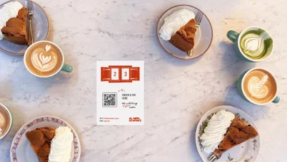 Cakes, lattes and QR table cards from above on marble