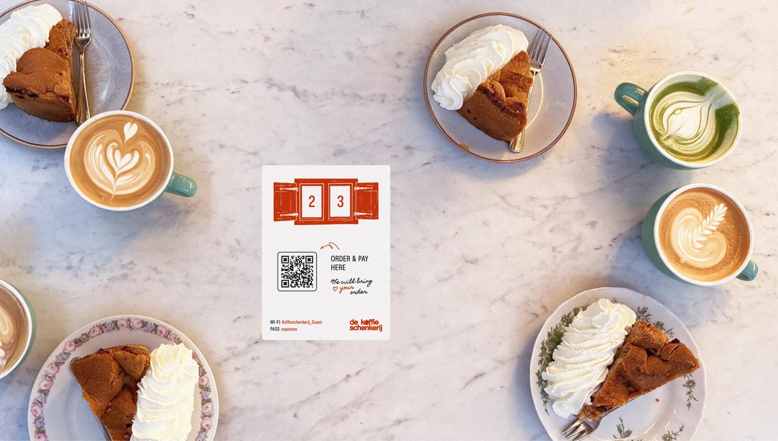 Cakes, lattes and QR table cards from above on marble