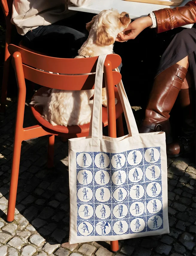 A dog beside a tote bag printed with Delft tiles