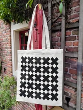 A checkerboard tote against the brick wall and red shutter